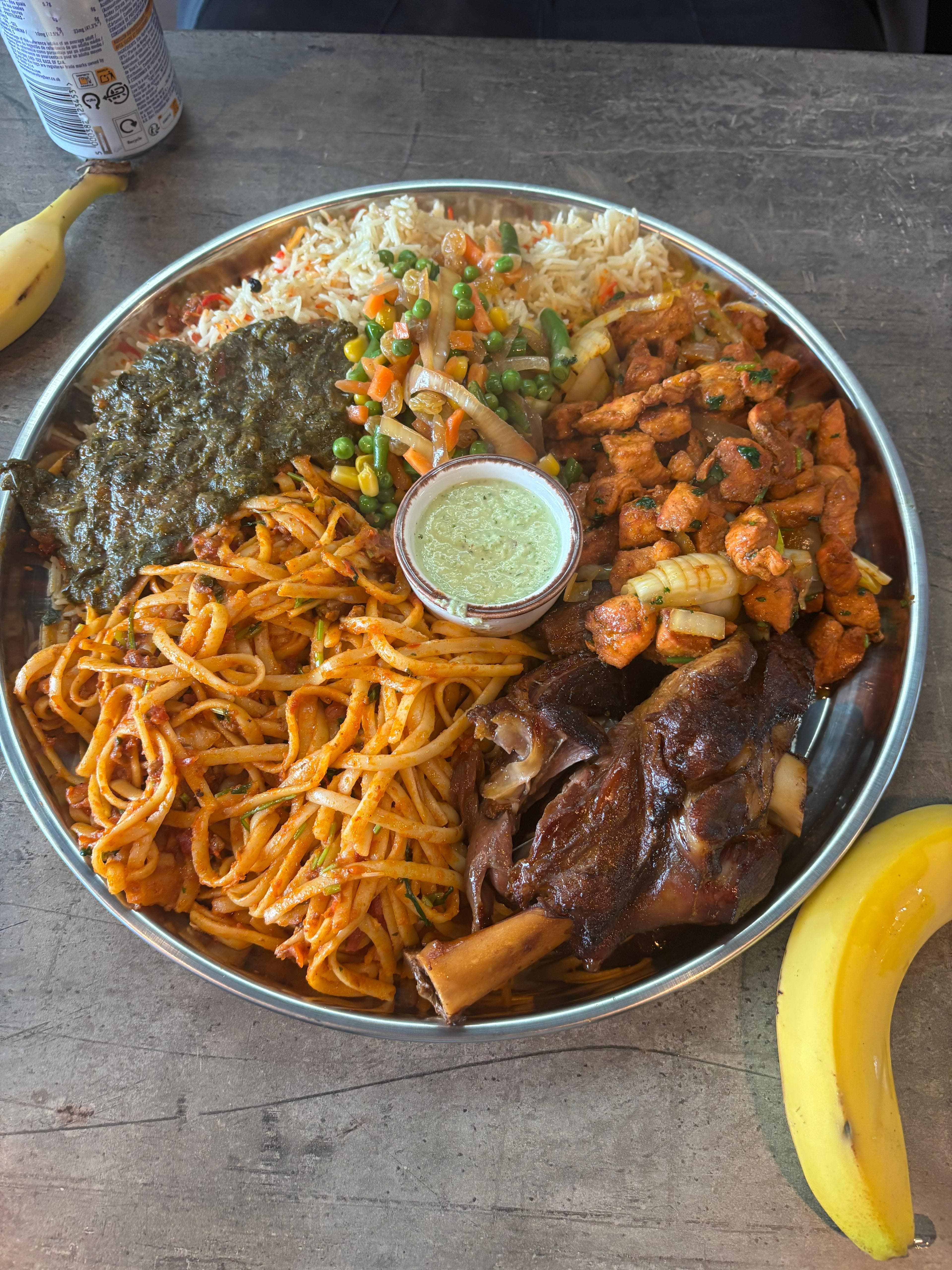 Somali food platter with rice, pasta, meat, vegetables and sauce
